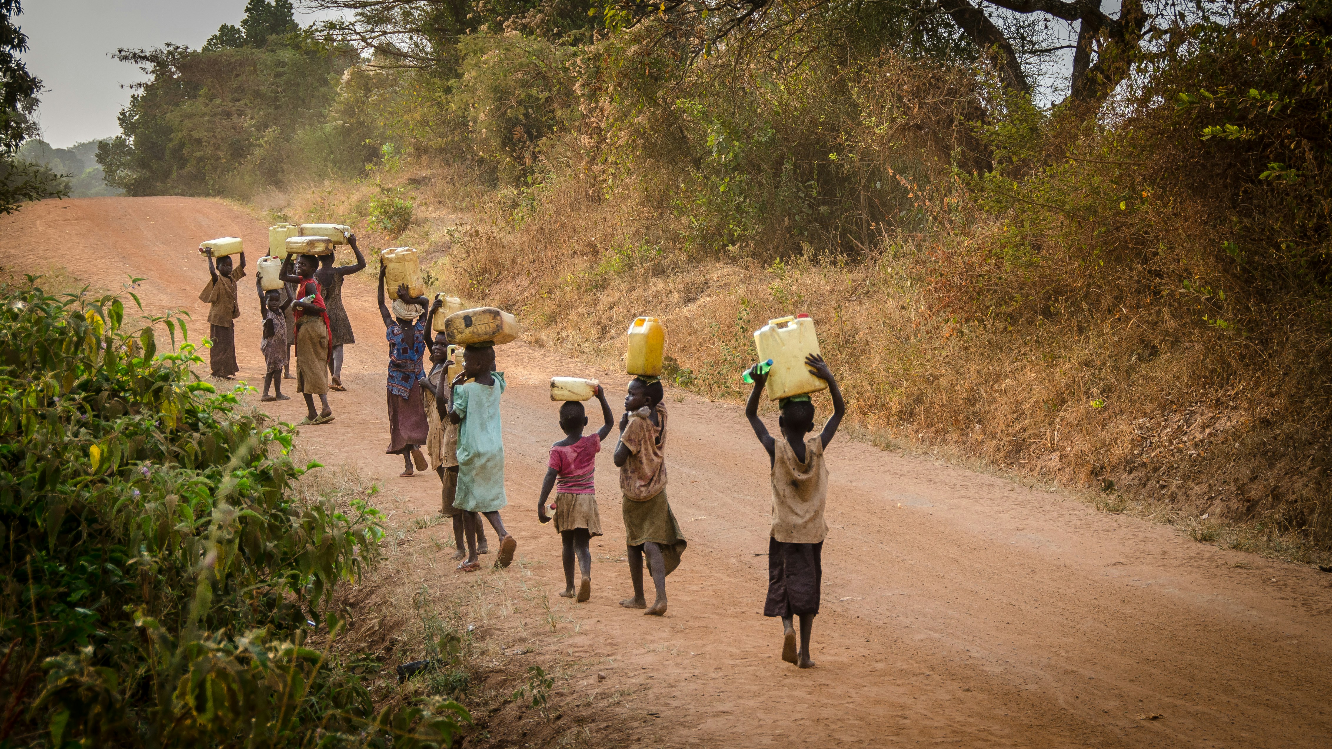 group of people coming back from the stream with their cans on their head showcasing africa nature